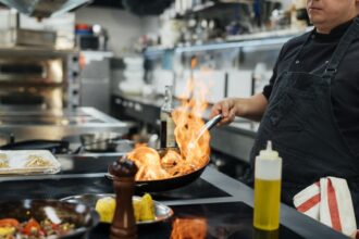 side view male chef flambeing dish Large
