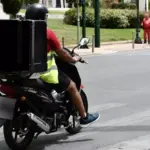 Διανομέας με δίκυκλο σε δρόμο κατά τη διάρκεια καύσωνα