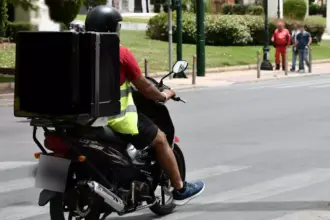 Διανομέας με δίκυκλο σε δρόμο κατά τη διάρκεια καύσωνα