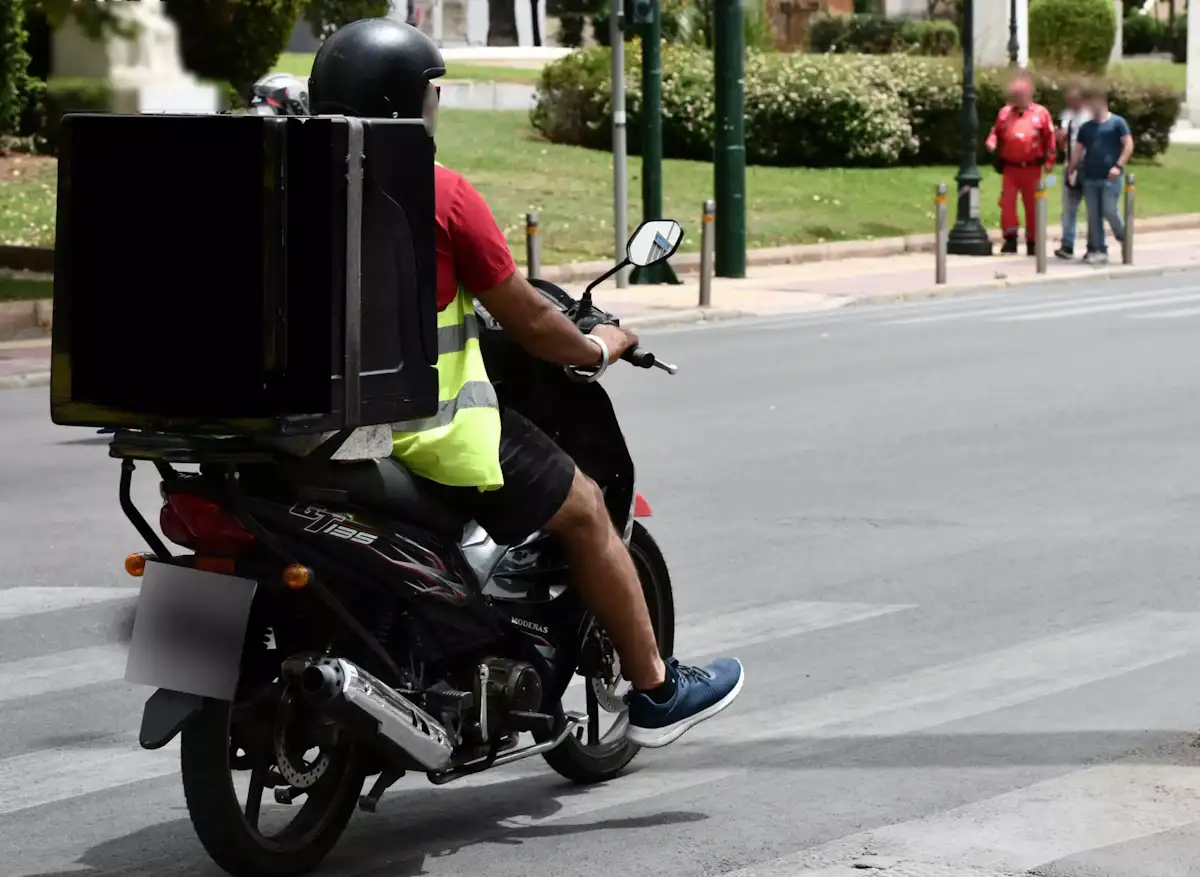Διανομέας με δίκυκλο σε δρόμο κατά τη διάρκεια καύσωνα