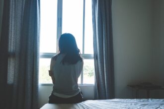 Γυναίκα σε εσωτερικό χώρο που κρατά το πρόσωπό της με τα χέρια