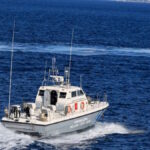 Πλοίο στο λιμάνι της Ελαφονήσου με ανοιχτό καταπέλτη και άνθρωπο στη θάλασσα να κολυμπά προς αυτό