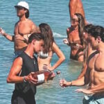 Σερβιτόρος μπαίνει στη θάλασσα για να σερβίρει πελάτη σε beach bar στην Πάρο