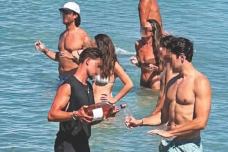 Σερβιτόρος μπαίνει στη θάλασσα για να σερβίρει πελάτη σε beach bar στην Πάρο
