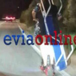 Δύο άτομα μεταφέρουν ξαπλώστρα θαλάσσης πάνω σε ηλεκτρικό πατίνι σε δρόμο από το Αλιβέρι προς τη Χαλκίδα